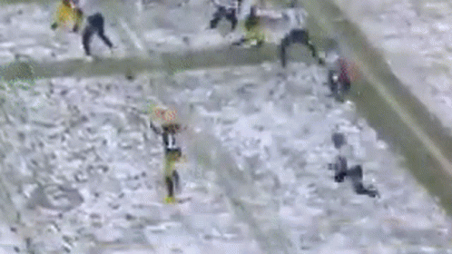 A Group Of People Are Playing A Game Of Football In The Snow On A Field . GIF