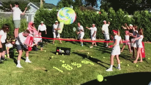 A Group Of People Are Playing A Game Of Tennis In A Grassy Area GIF