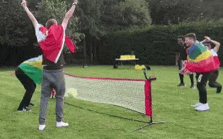 A Group Of People Are Playing A Game Of Tennis On A Grassy Field GIF