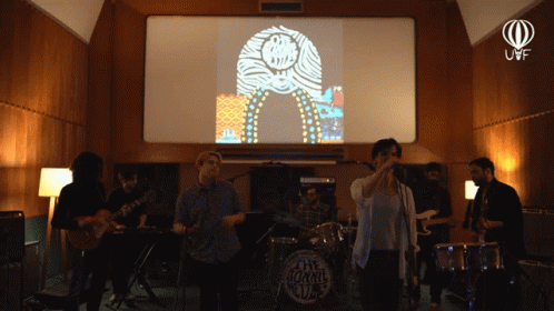 A Group Of People Are Playing Instruments In Front Of A Screen That Says The Jukebox Club GIF