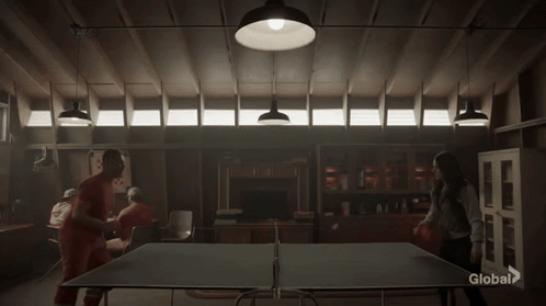 A Group Of People Are Playing Ping Pong In A Dark Room With A Sign That Says Global On It GIF