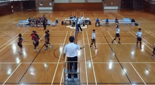 A Group Of People Are Playing Volleyball On A Court While A Referee Watches . GIF