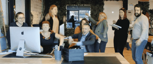 A Group Of People Are Posing For A Photo In Front Of An Apple Computer Monitor GIF