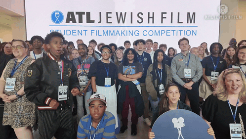 A Group Of People Are Posing For A Picture In Front Of A Sign That Says Atl Jewish Film GIF