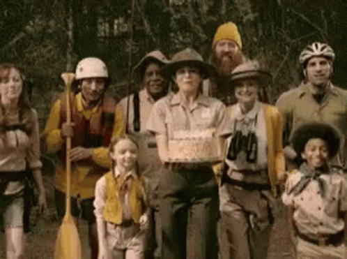 A Group Of People Are Posing For A Picture With A Woman Holding A Cake GIF