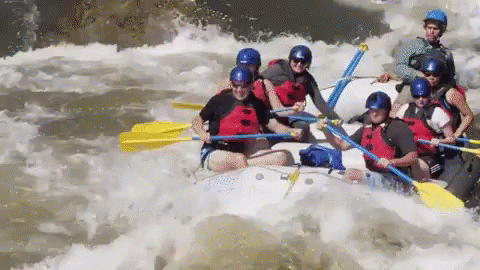 A Group Of People Are Rafting Down A River In A White Raft GIF