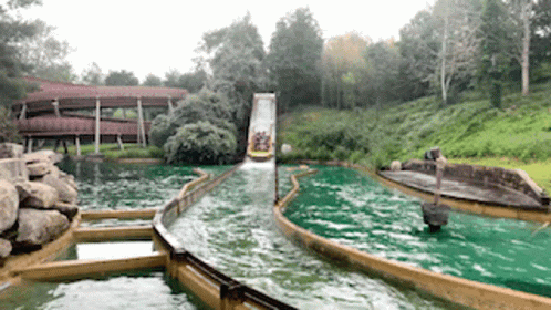 A Group Of People Are Riding A Boat Down A Water Slide . GIF