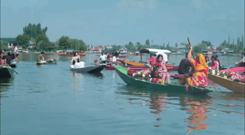 A Group Of People Are Riding In Boats On A Lake GIF