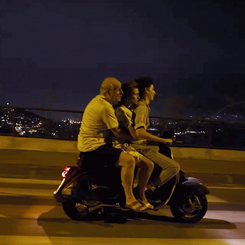 A Group Of People Are Riding On A Scooter At Night GIF
