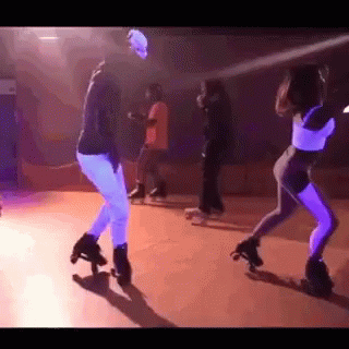 A Group Of People Are Rollerblading In A Dark Room With Purple Lights . GIF