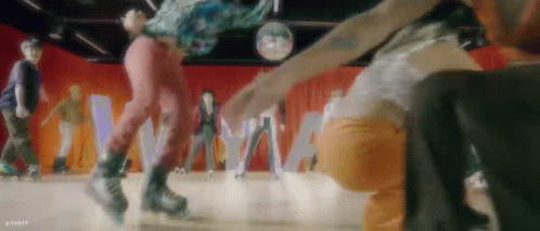 A Group Of People Are Rollerblading In A Room With A Disco Ball In The Background . GIF