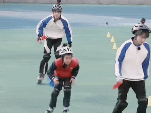 A Group Of People Are Rollerblading On A Field And One Of Them Is Wearing A Helmet GIF