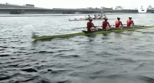 a group of people are rowing a boat on a lake with the olympic logo in the background