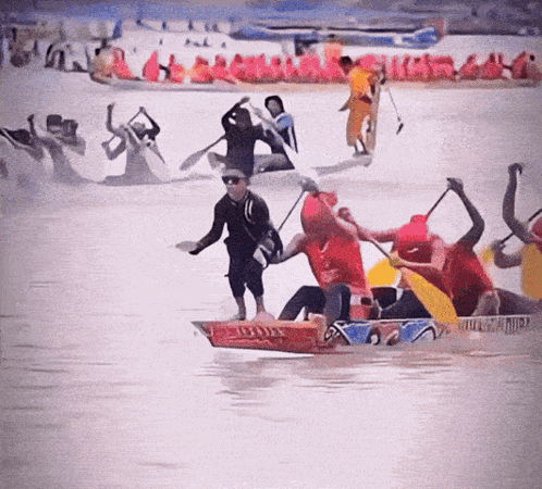 A Group Of People Are Rowing Boats In The Water And One Of Them Is Wearing A Shirt That Says ' Red Bull ' On It GIF