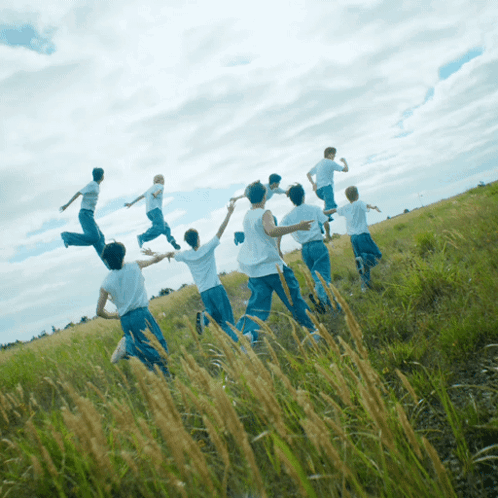 A Group Of People Are Running In A Field With Their Arms Outstretched GIF