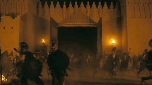 A Group Of People Are Running In Front Of A Building With The Doors Open GIF