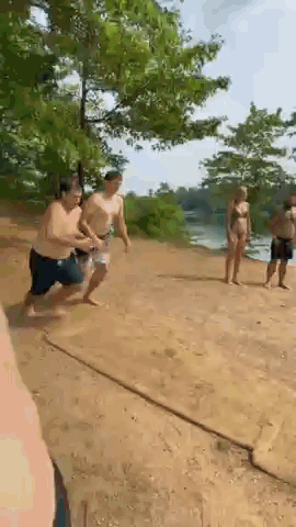 A Group Of People Are Running On A Dirt Road . GIF