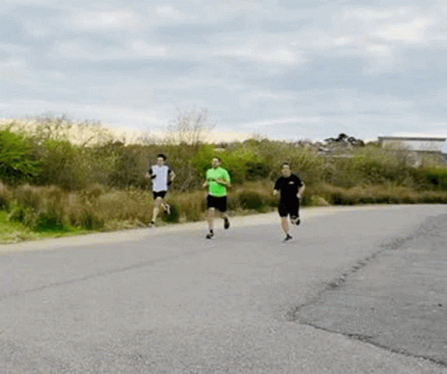 A Group Of People Are Running On A Road . GIF