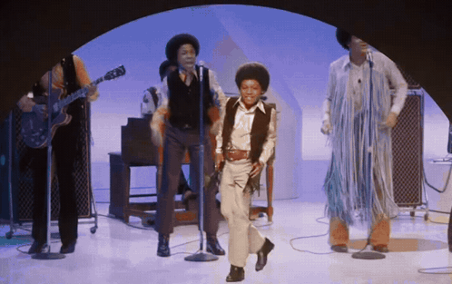 A Group Of People Are Singing And Dancing On Stage GIF