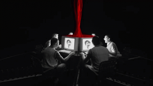 A Group Of People Are Sitting Around A Table Looking At Computers GIF