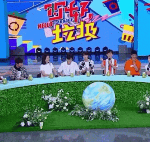 A Group Of People Are Sitting Around A Table With A Globe In The Middle Of The Table . GIF