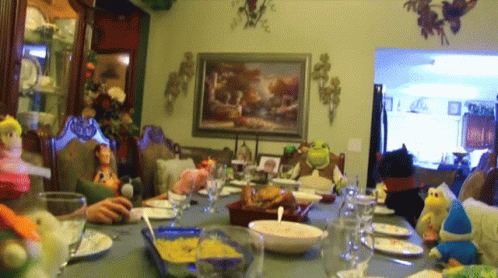 A Group Of People Are Sitting Around A Table With Plates And Glasses GIF
