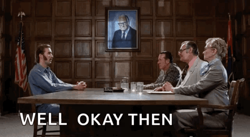 A Group Of People Are Sitting Around A Table With The Words Well Okay Then Written On The Bottom GIF