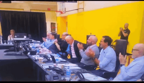 A Group Of People Are Sitting At A Table Clapping GIF