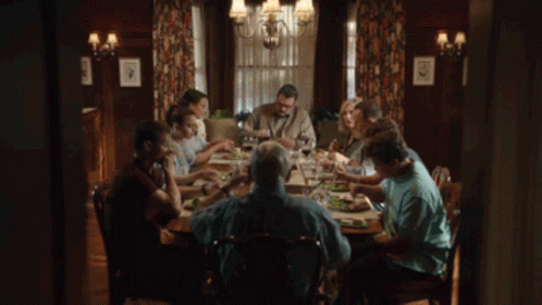 A Group Of People Are Sitting At A Table Eating Food GIF