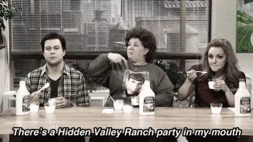 a group of people are sitting at a table eating ranch