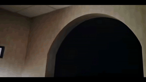 A Group Of People Are Sitting At A Table In A Dark Room With Arches . GIF