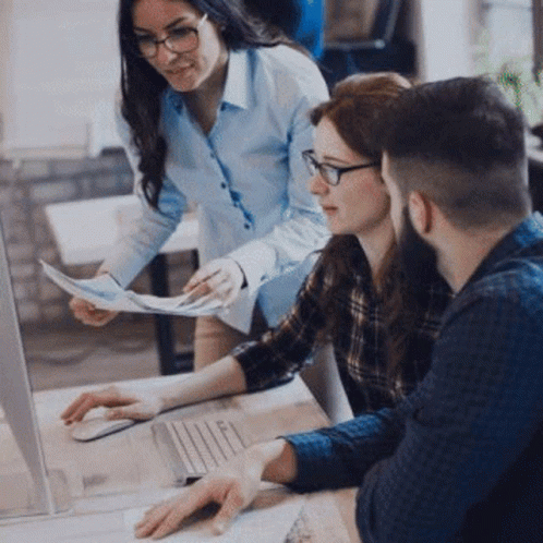 A Group Of People Are Sitting At A Table Looking At A Laptop Computer . GIF