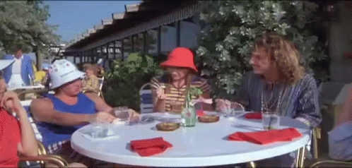 A Group Of People Are Sitting At A Table With Drinks And Napkins . GIF