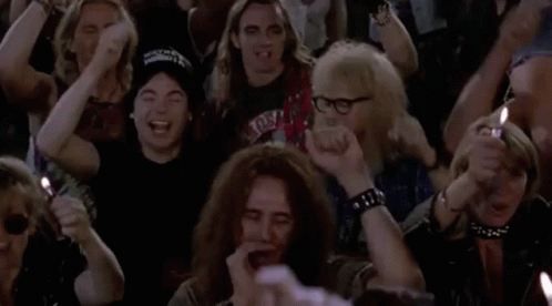 A Group Of People Are Sitting In A Crowd Holding Candles And Lighter . GIF