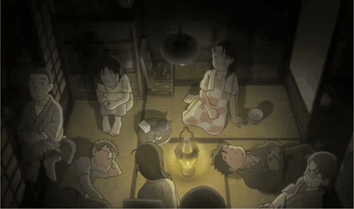 a group of people are sitting in a dark room with a lantern in the middle
