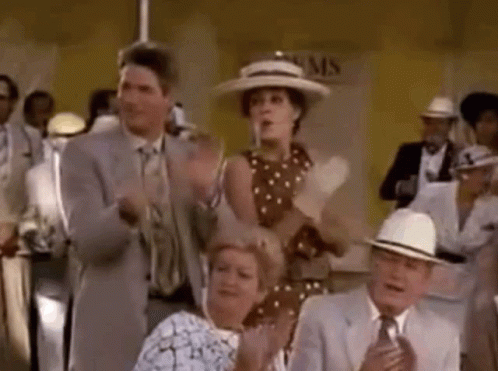 A Group Of People Are Sitting In A Room Clapping Their Hands In A Crowd . GIF