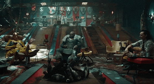 A Group Of People Are Sitting In A Room With A Bowling Alley And A Sign That Says S GIF