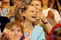 A Group Of People Are Sitting In A Stadium And One Woman Is Laughing GIF