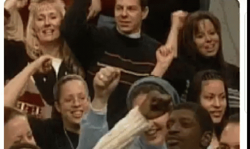 A Group Of People Are Sitting In A Stadium Holding Their Fists In The Air . GIF