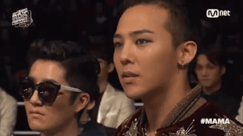 A Group Of People Are Sitting In A Stadium Watching A Concert . GIF