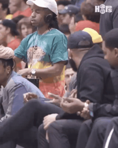 A Group Of People Are Sitting In A Stadium Watching A Game . GIF