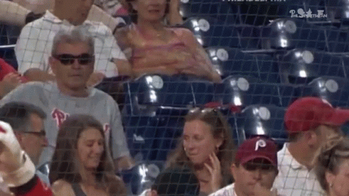 A Group Of People Are Sitting In A Stadium Watching A Game . GIF
