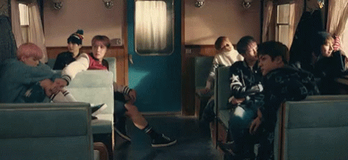 A Group Of People Are Sitting In A Train Car Talking To Each Other . GIF