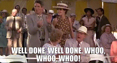 A Group Of People Are Sitting In Chairs And A Man Is Standing In Front Of Them . GIF