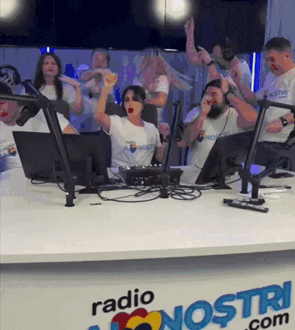 A Group Of People Are Sitting In Front Of A Desk That Says Radio Nostri.com GIF