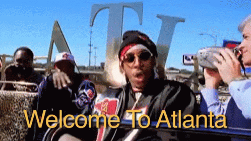 A Group Of People Are Sitting In Front Of A Sign That Says Welcome To Atlanta On It GIF