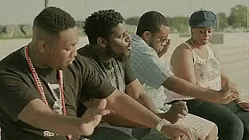 A Group Of People Are Sitting Next To Each Other In A Row . GIF