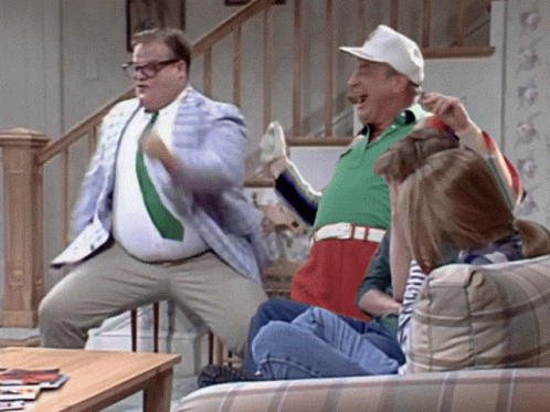 A Group Of People Are Sitting On A Couch And One Man Is Standing On A Chair GIF