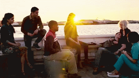 A Group Of People Are Sitting On A Dock Near A Body Of Water GIF