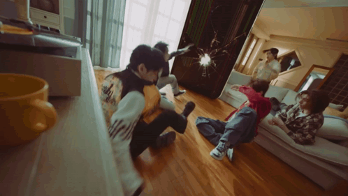 a group of people are sitting on the floor in a living room and one of them has the word adidas on his back